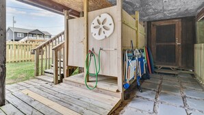 A wooden deck with a wooden door and a green hose.