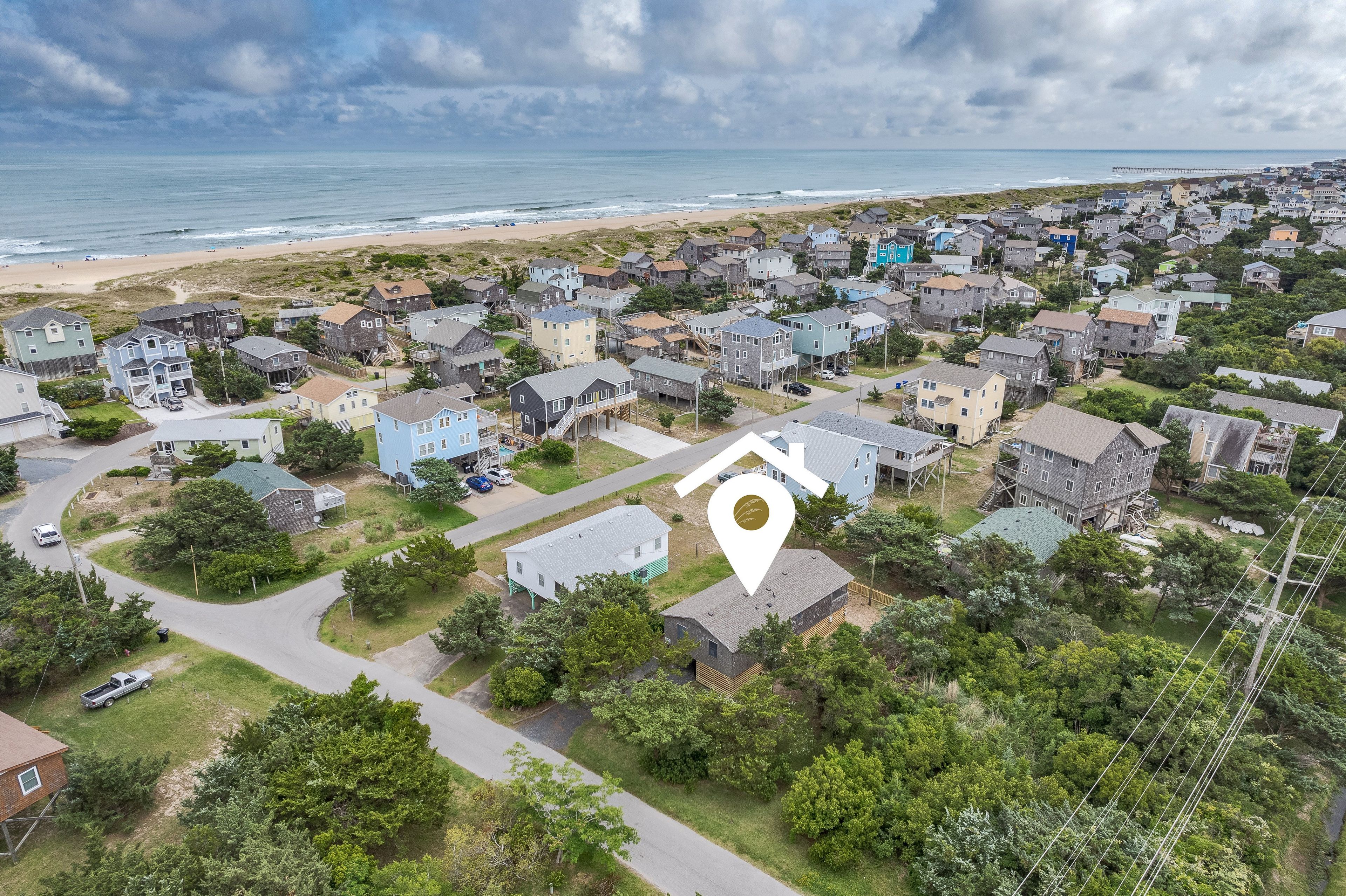 A coastal residential area with houses, a beach, and a pier.