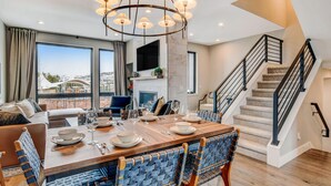 A modern living room with a dining area, a fireplace, and a staircase. - Downtown WP Event Center Loft 96 I Rooftop Spa I Great Views I Bunks I Discounted Attractions (Winter Park)