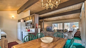 A cozy living area with a wooden dining table, green chairs, a sofa, and a television. - Mammoth Lakes Townhome < 2 Mi to Ski Area! (Mammoth Lakes)
