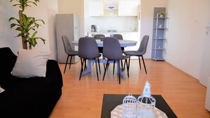 Ein kompakter Wohnraum mit Essbereich, einer schwarzen Couch, einem Blumentopf und einem dekorativen Tisch mit Vogelkäfigen.