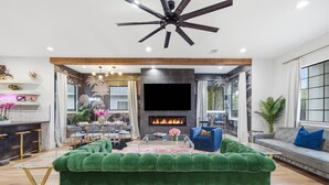 Ein modernes Wohnzimmer mit Kamin, einem grünen Sofa und einem Deckenventilator.