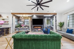 Una sala de estar moderna con chimenea, sofá verde y ventilador de techo.