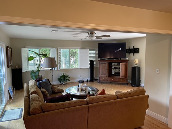 A living room with a sectional sofa, a coffee table, a TV, and a ceiling fan.