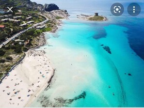 An aerial view of a coastal area with a beach, clear turquoise waters, and a small island with a structure. - Suite Guest House a few steps from the sea (Ottava)