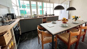 Una cocina moderna con comedor, ventanas amplias y suelo de piedra.