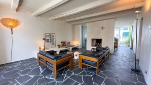 Una sala de estar acogedora con suelo de piedra, chimenea y un área de descanso con sofá y sillones.