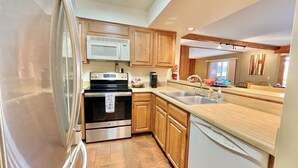 Una cocina con armarios de madera, electrodomésticos de acero inoxidable y piso de baldosas.