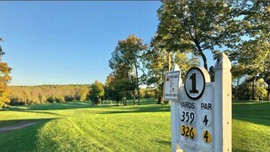 Señal de campo de golf que indica los números de hoyos y las distancias.