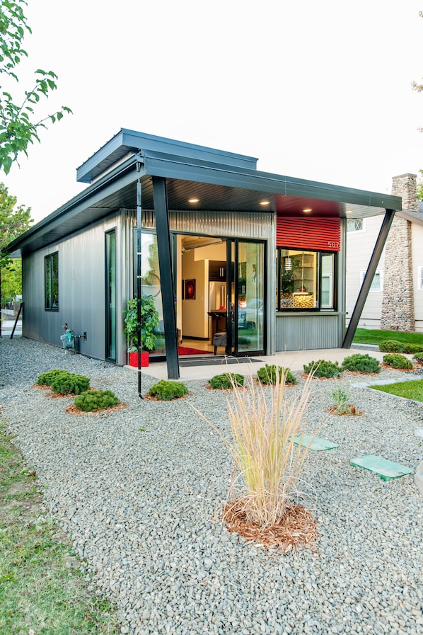 A modern building with a metal exterior, large windows, and a red awning. - Modern Tiny Home Steps from the Heart of Fruita (Fruita)