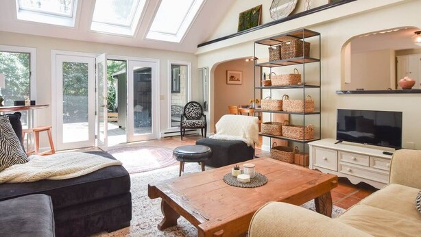 A spacious living room with a large window, a fireplace, a television, and a bookshelf.