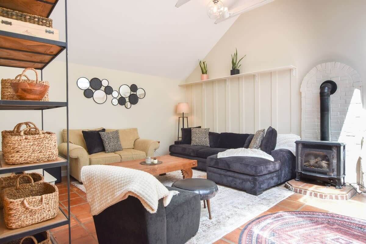 Una sala de estar acogedora con chimenea, un conjunto de sofás, una mesa de centro y una estantería con cestas.