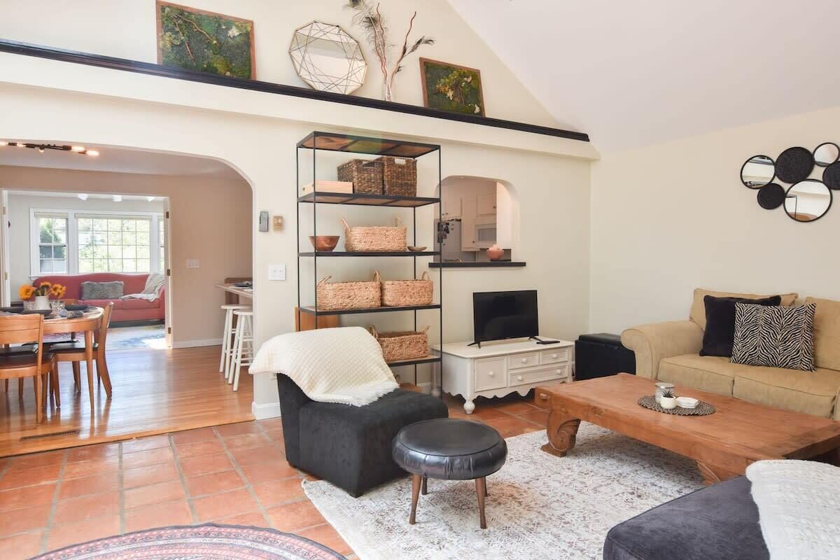 Ein Wohnzimmer mit Sofa, Hocker, Couchtisch und Bücherregal.