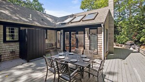 A covered patio with a dining table and chairs, a chimney, and a view of the backyard.