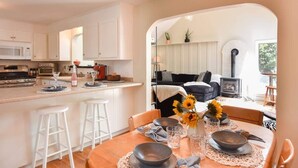 A modern kitchen with white cabinets, a central island with stools, and a dining area with a table set for two.