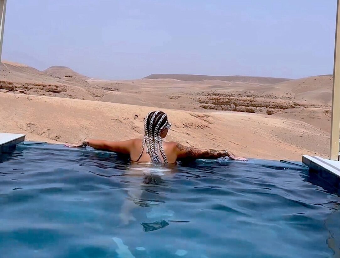 Una persona en una piscina, con un paisaje desértico al fondo.