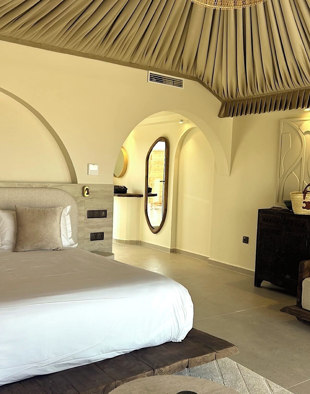 A spacious bedroom with a large bed, a dresser, and a mirror.
