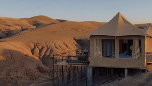 Ein Zelt in der Wüste mit schlichtem, zweckmäßigem Design, umgeben von Sanddünen.
