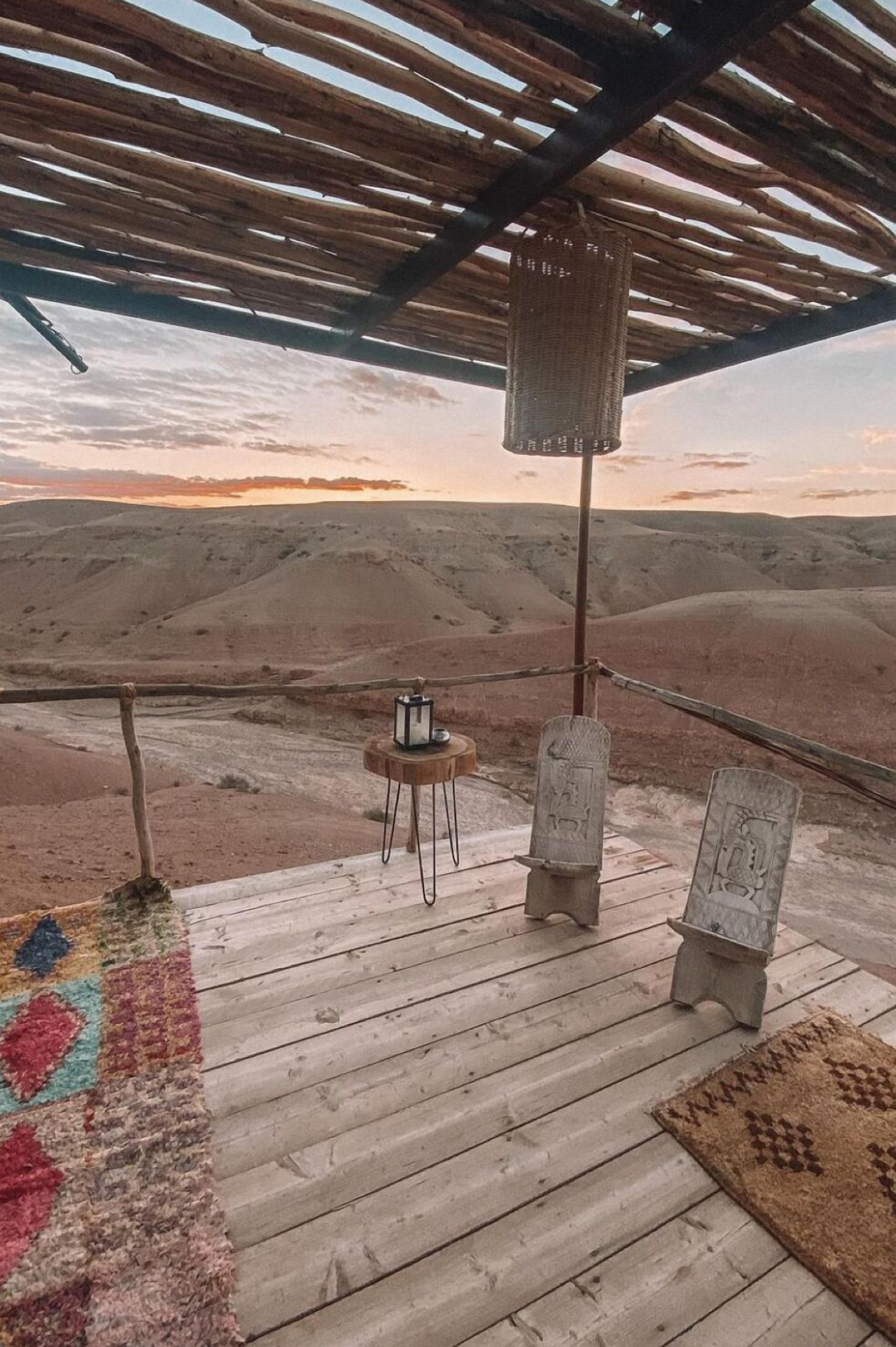 Una terraza de madera con una pérgola rústica, un farolillo y una alfombra.
