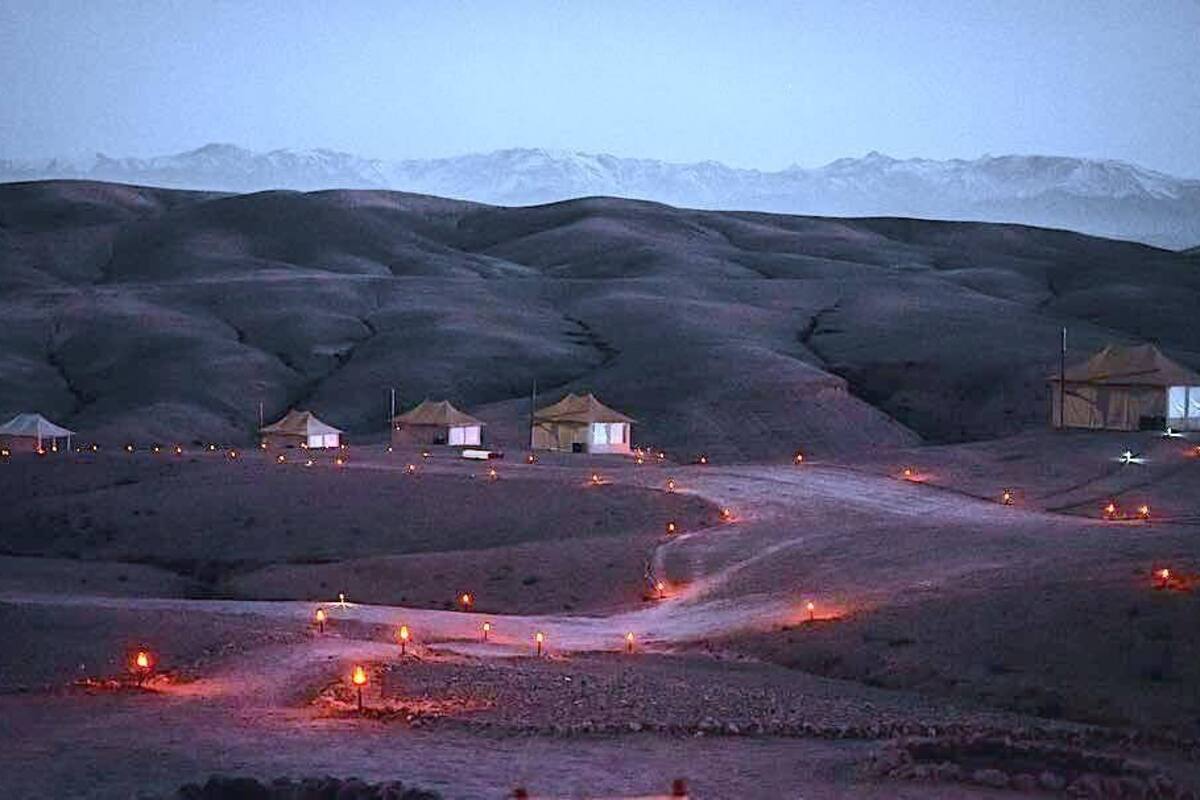 A series of tents in a hilly, barren landscape with distant mountains.