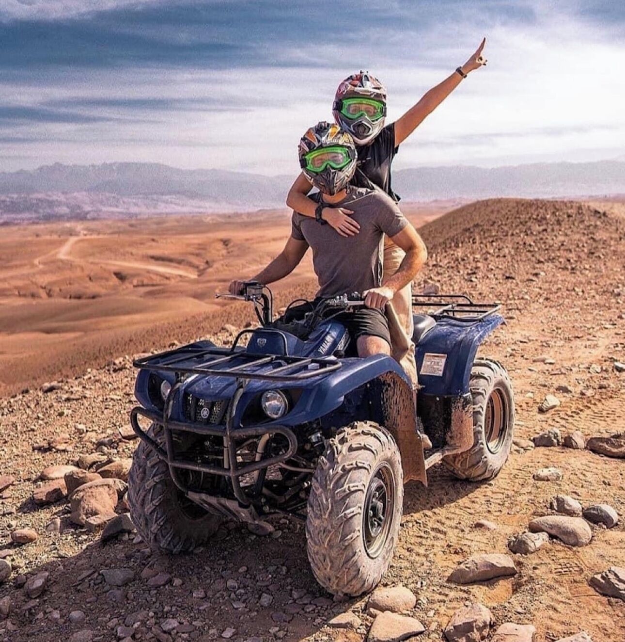 Two people on an ATV in a desert landscape.