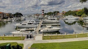 A marina with multiple boats docked, a prominent lighthouse in the background, and buildings along the waterfront. - 949 Cutter Court at The Sea Pines Resort (Hilton Head Island)