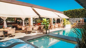 A poolside area with lounge chairs, umbrellas, and potted plants.