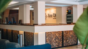 A reception area with a sign reading "Eco City Hotel," a reception desk, and a seating area with a blue couch.