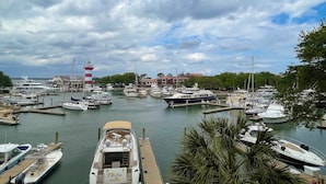 A marina with various boats docked, a lighthouse, and buildings in the background. - 1034 Caravel Court at The Sea Pines Resort (Hilton Head Island)