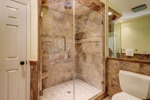A glass-enclosed shower with a marble floor, a toilet, and a sink with a mirror. - 1100 Harbour South Club at The Sea Pines Resort (Hilton Head Island)
