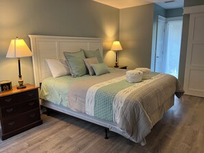 A neatly made bed with a quilted bedspread, two bedside lamps, a wooden nightstand with drawers, and a door to the right. - 1259 Harbour Town Club at The Sea Pines Resort (Hilton Head Island)