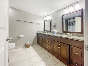Ein Badezimmer mit Toilette, Bidet, Waschtisch mit Spiegel und Handtuchhalter.