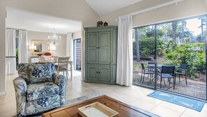 Amplia sala de estar con sofá, un aparador y un juego de comedor. Hay una puerta corrediza de vidrio que da a un patio exterior.