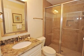 A bathroom with a marble sink, a toilet, a glass-enclosed shower, and a large mirror. - 2219 Heritage at The Sea Pines Resort (Hilton Head Island)