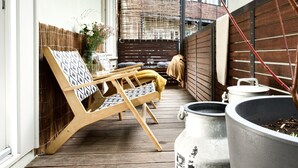 En træterrasse med to liggestole, et bord og to store krukker.