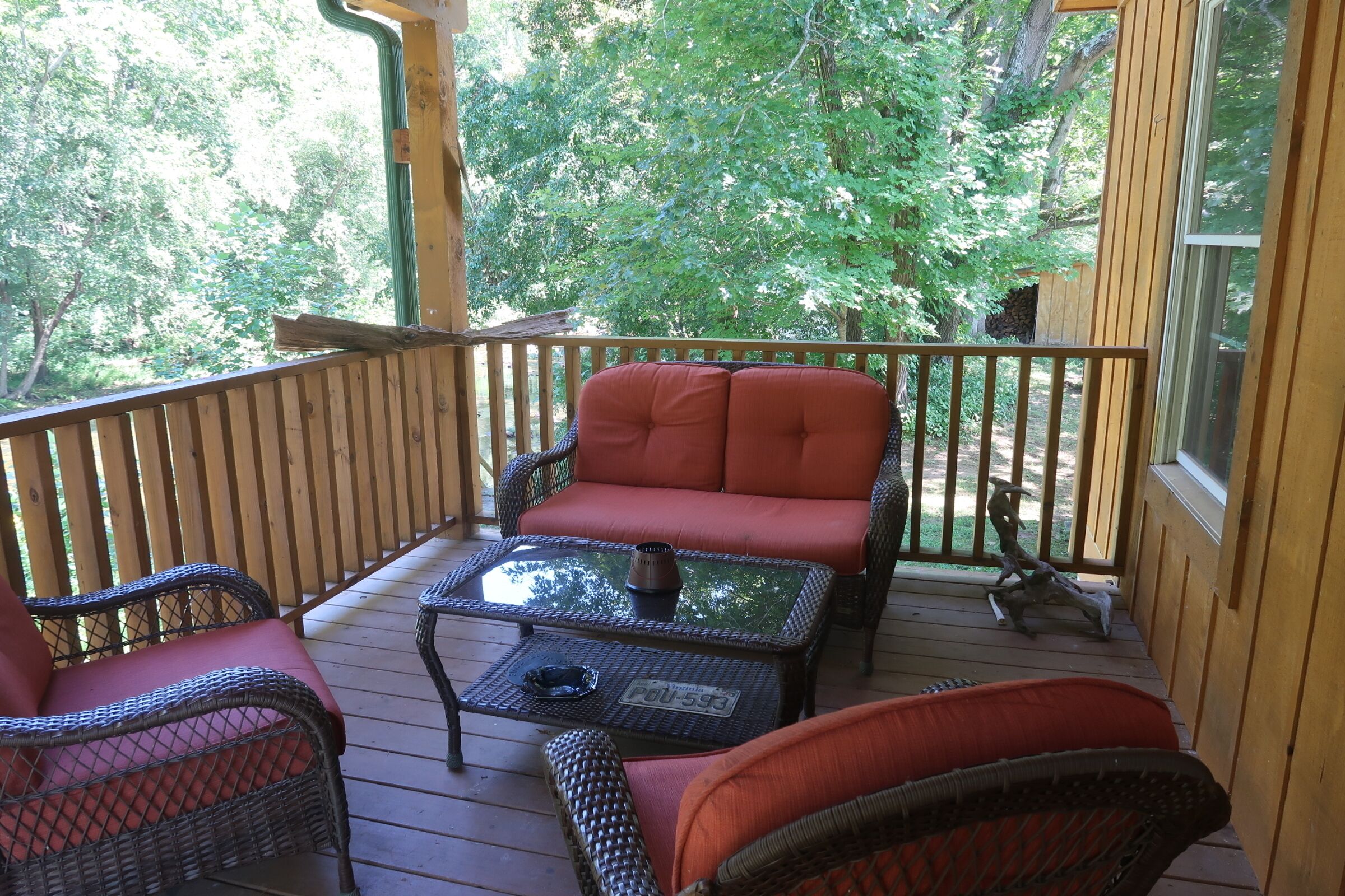 Une terrasse en bois avec des meubles en osier et une table en verre.