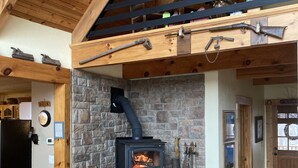 Ein rustikales Interieur mit Kamin aus Stein, Holzbalken und einem Holzstuhl.