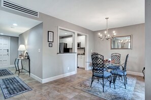 A dining area with a chandelier, a table with chairs, and a kitchen in the background. - 2236 Heritage at The Sea Pines Resort (Hilton Head Island)