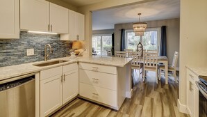 A kitchen with white cabinets, a tiled backsplash, and a dining area with a chandelier. - 2265 Heritage at The Sea Pines Resort (Hilton Head Island)