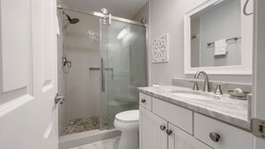 A modern bathroom with a glass-enclosed shower, a toilet, a sink with a marble countertop, and a mirror above the sink. - 2270 Heritage at The Sea Pines Resort (Hilton Head Island)
