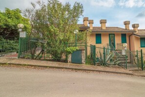 Un edificio con un cancello verde, un muro in pietra e un albero.