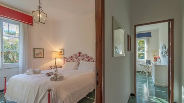 A hotel room with a bed, a nightstand, a lamp, a mirror, and a view of the outside.