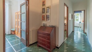 A hallway with a wooden dresser, a radiator, and framed pictures on the wall.
