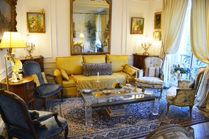 Un salon traditionnel avec un canapé, des fauteuils, une table basse et un grand miroir.