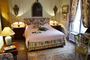 Une chambre à coucher avec une couvre-lit à motifs floraux, une tête de lit en bois et une table de chevet avec une lampe.