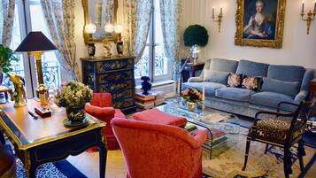 Une pièce avec un canapé bleu, un fauteuil rouge, une table en bois avec une lampe et un miroir décoratif.