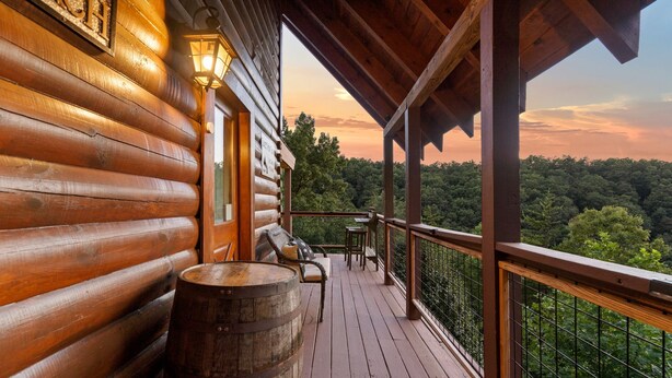 A wooden cabin with a balcony overlooking a forested area. - Stunning Sunset Views! Hot Tub, 2 Fire Pits, Game Loft, Dogs Welcome, Pool Open! (Sevierville)