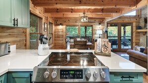 A modern kitchen with a central island, wooden ceiling, and large windows. - Stunning Sunset Views! Hot Tub, 2 Fire Pits, Game Loft, Dogs Welcome, Pool Open! (Sevierville)