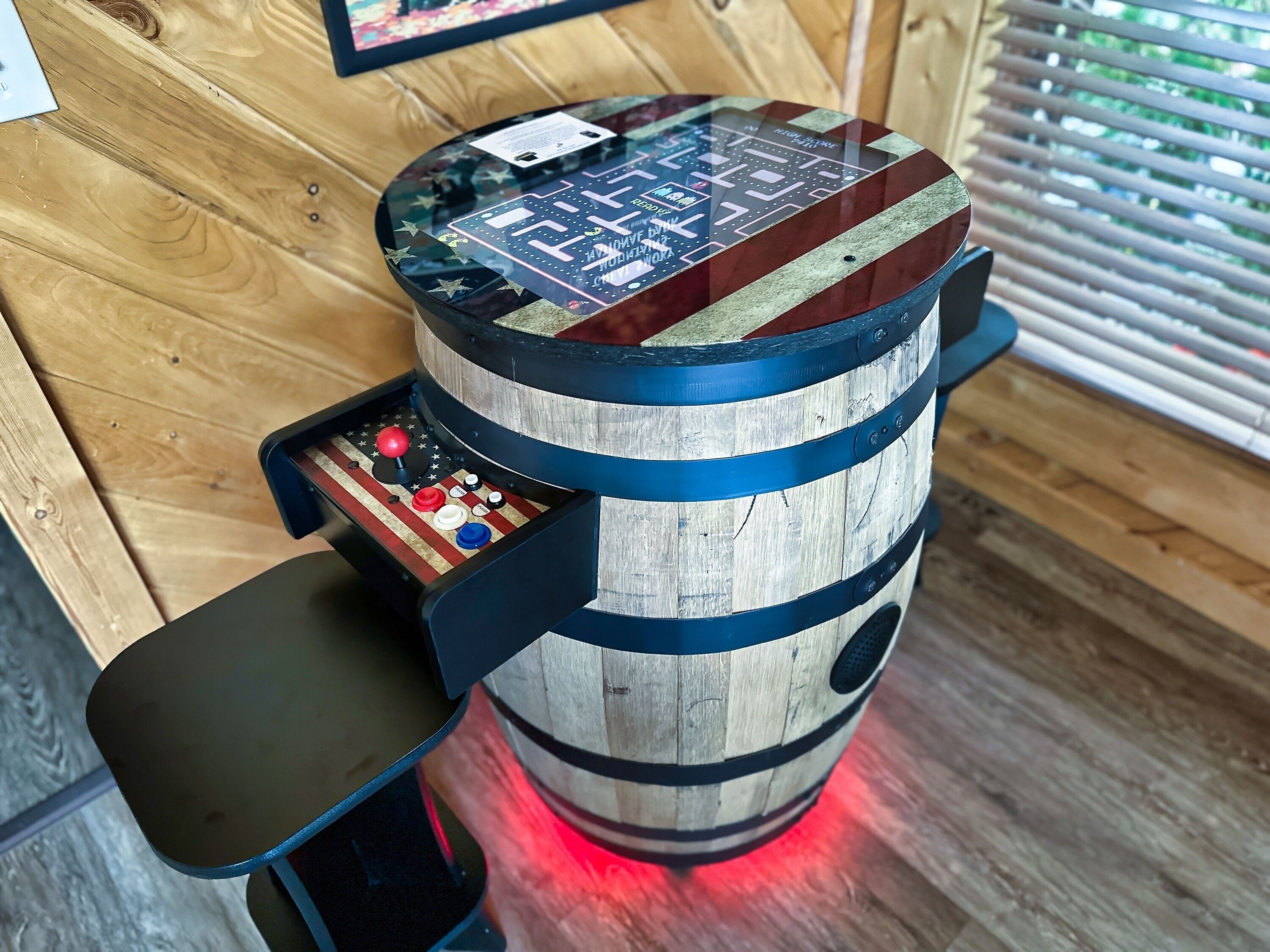 A wooden barrel-shaped object with a digital interface and a small table attached to it.
