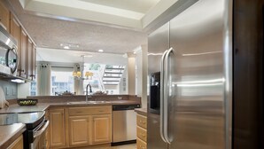 Une cuisine moderne dotée d’appareils électroménagers en acier inoxydable, de meubles en bois et d’un îlot central.